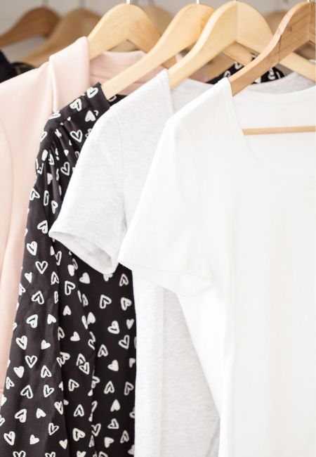 Clothes Closet with two white shirts, one black one and one pink