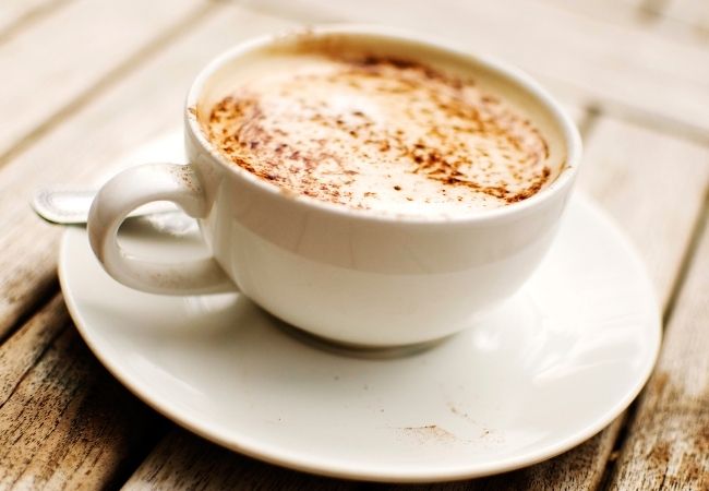 Latte in a white cup and saucer sprinkled with cinnamon 