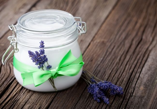 Mason jar with epsom salts with lavender sprig tied with a ribbon on front 
